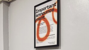 Un panneau encadré avec du texte, accroché au mur, un plateau de verres et une boîte en bois.