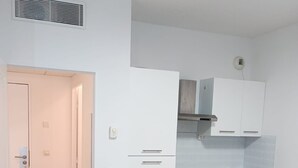 A compact kitchen with white cabinets, a built-in oven, and a stainless steel sink. - Charming apartment for 4 people with a terrace and air conditioning (Grasse)