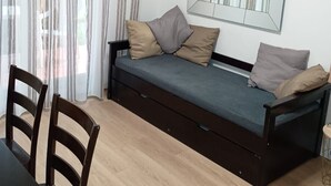 A room with a sofa bed, a dining table, chairs, a mirror, and sheer curtains. - Charming apartment for 4 people with a terrace and air conditioning (Grasse)