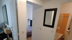 A hallway with a bed, a mirror, and a bathroom with a bathtub. - Charming apartment for 4 people with a terrace and air conditioning (Grasse)