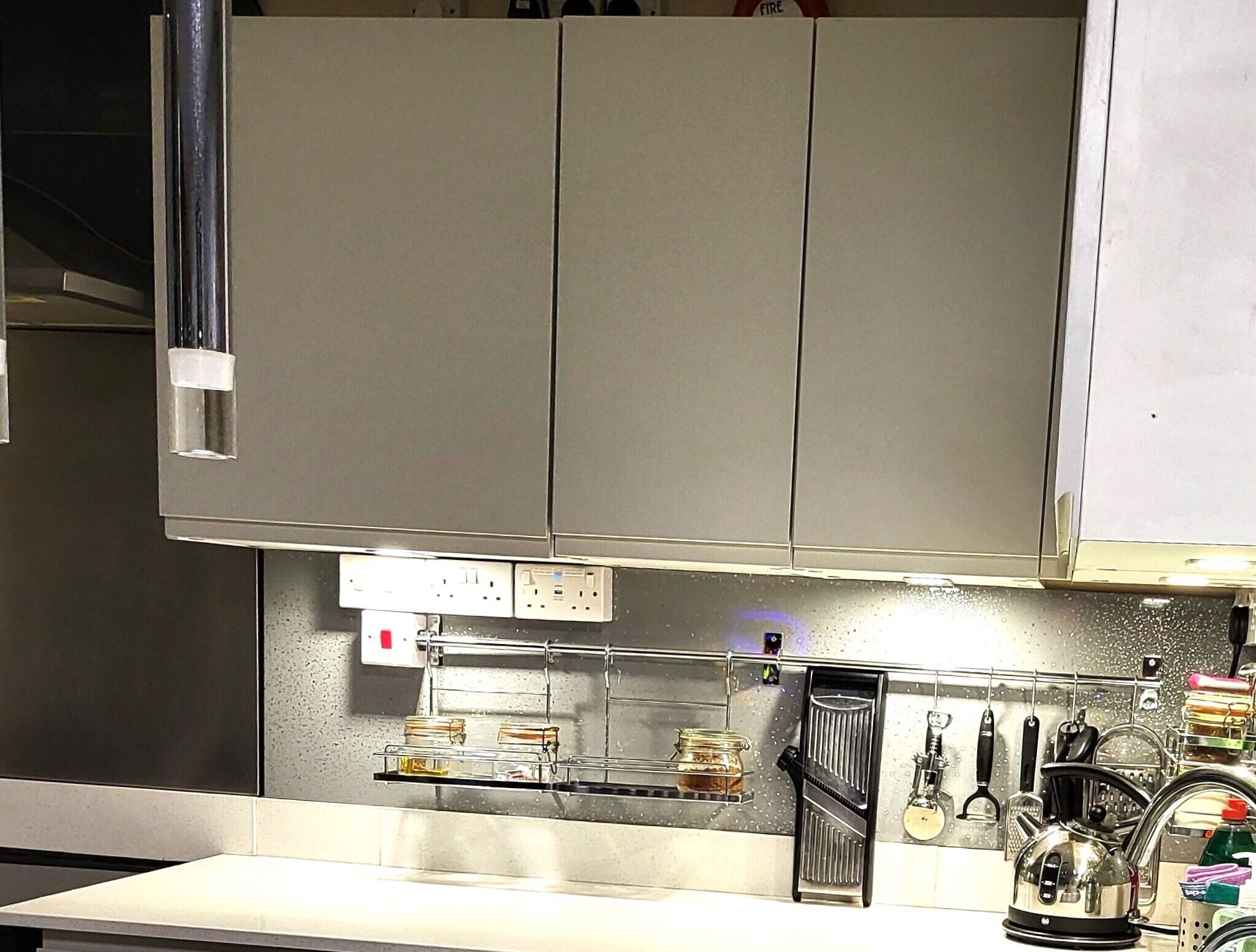 Una cucina con mobili in acciaio inossidabile, un piano di lavoro con un bollitore e diversi utensili da cucina.