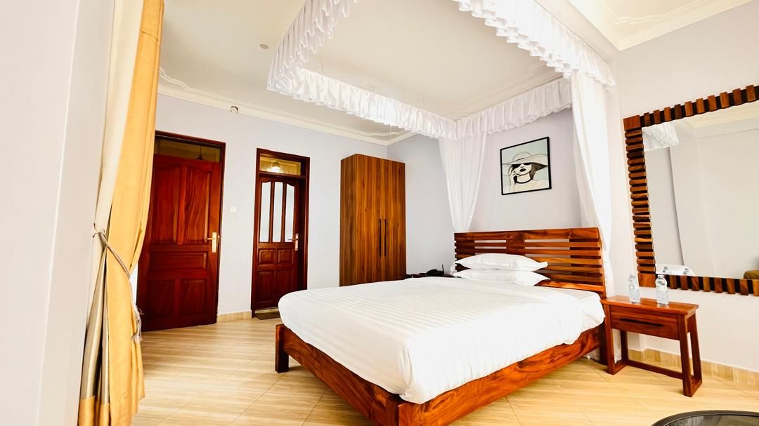 A bedroom with a wooden bed, a bedside table, a mirror, and a door.