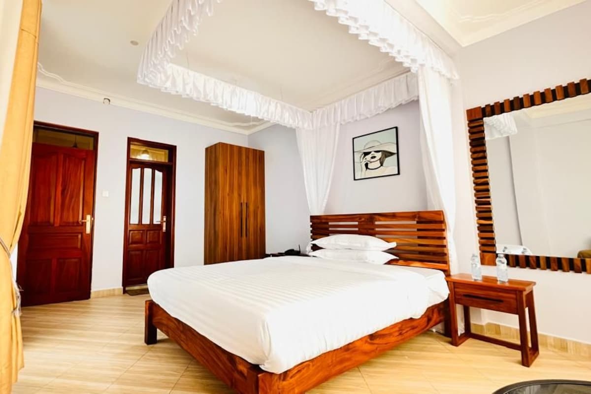 Un dormitorio con una cama de madera, una mesita de noche, un espejo y una puerta.