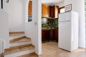 Eine Küche mit Holdekor-Schränken, einem weißen Kühlschrank und einer gefliesten Spritzschutzwand.
