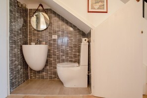A bathroom with a modern design, featuring a white toilet, a round mirror, and a unique sink. - ISOLA ALTA - BUDONI SWEET HOME (Porto Ottiolu)