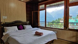 Ein Schlafzimmer mit Holzwänden, einem Bett, großen Fenstern und Bergblick.