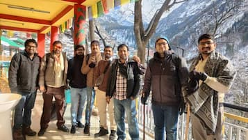A group of people standing on a terrace with a mountain view.