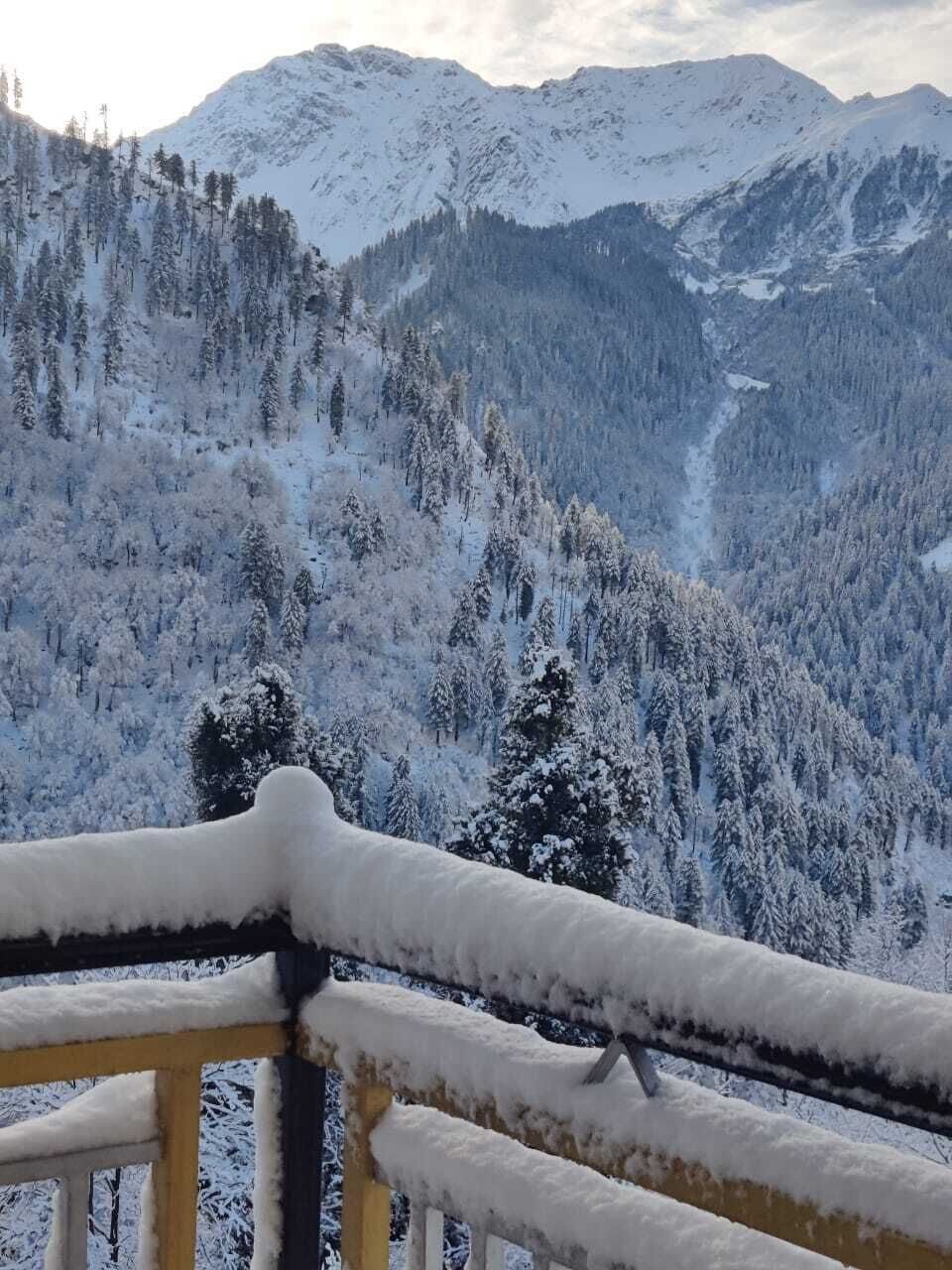 A snowy mountain landscape with a wooden railing in the foreground.