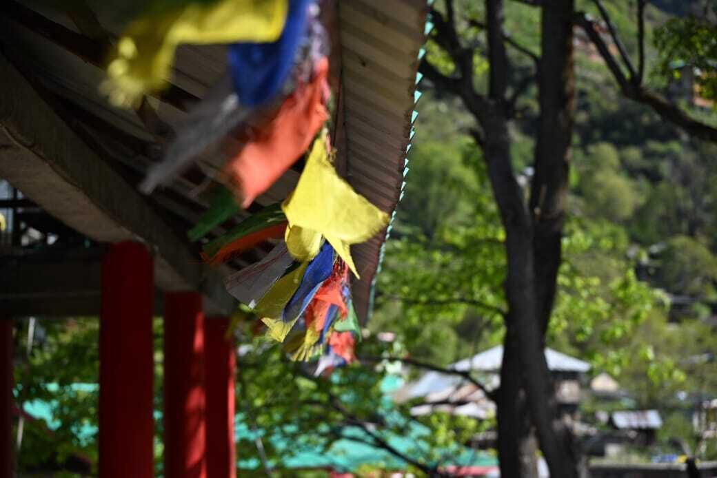 A structure with colorful flags, red pillars, and a blurred background of trees and buildings.