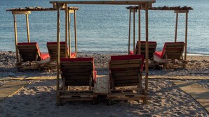 A beach with wooden lounge chairs and a wooden pergola structure.