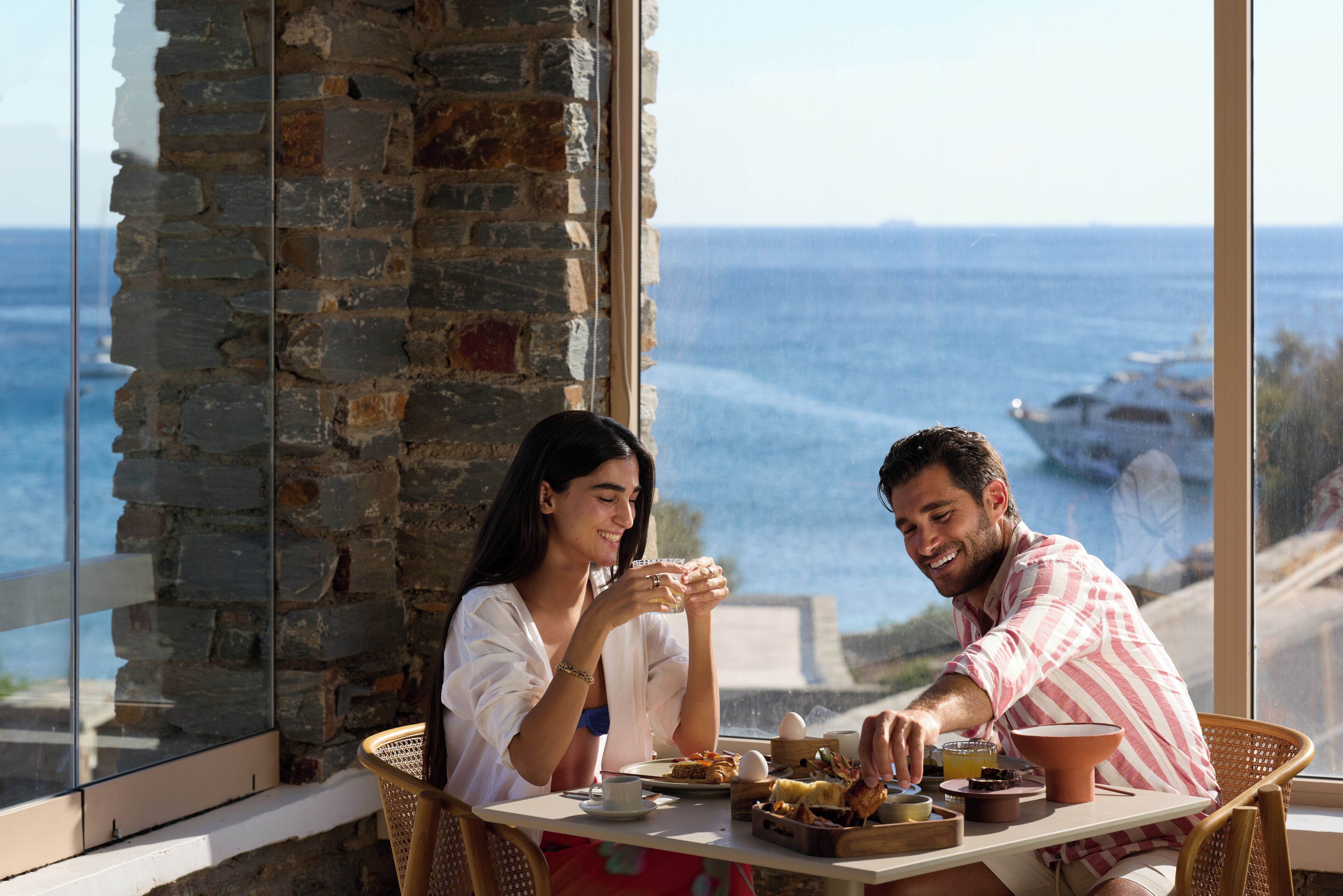 Um casal jantando à mesa com vista para o mar.