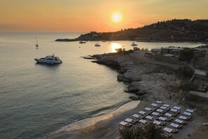 A coastal area with boats, a beach with sun loungers, and buildings on a hillside. - Domotel Kea (Kea)