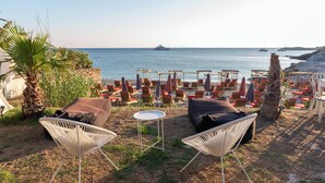 A beachside lounge with outdoor seating, a small table, and a view of the sea.