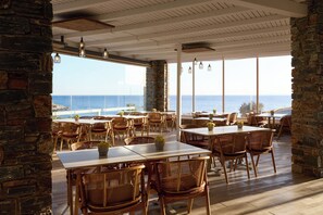 A restaurant with tables and chairs, large windows, and a view of the sea. - Domotel Kea (Kea)