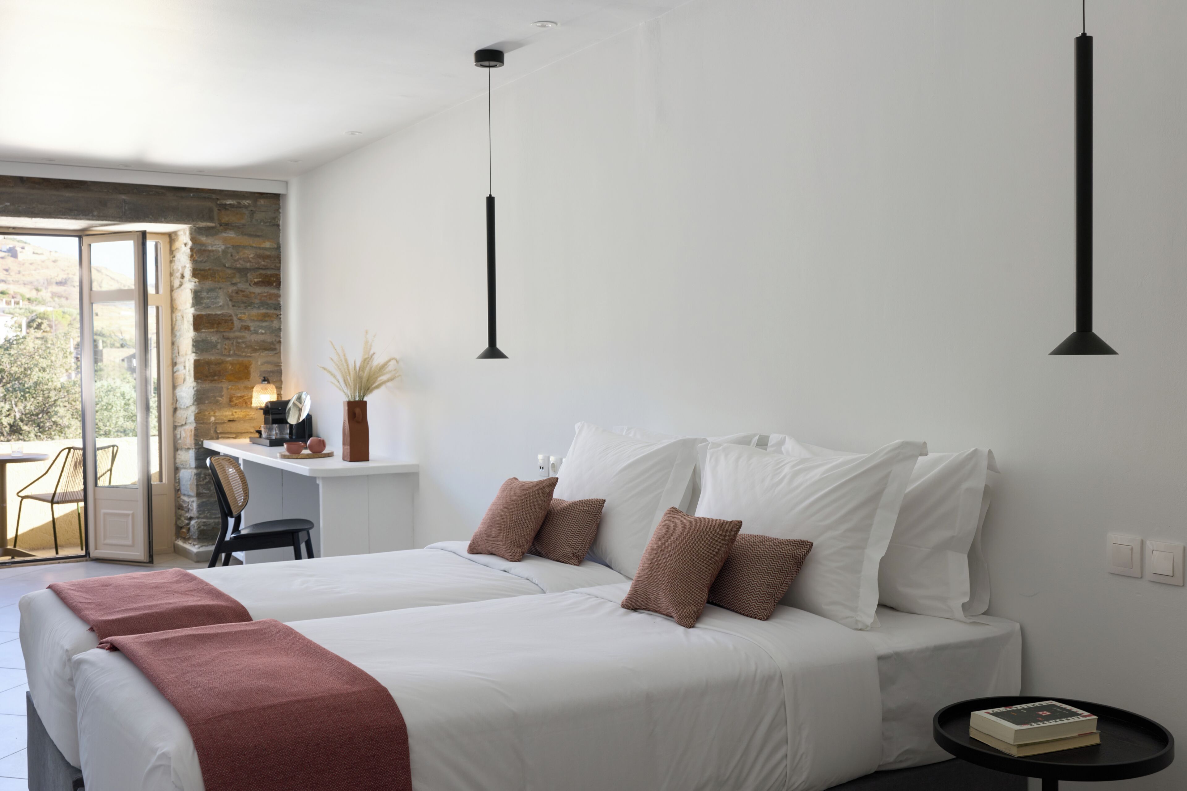 A modern bedroom with a large bed, a small desk, and a view through an open door.