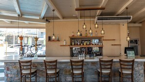 A bar area with a stone counter, wooden chairs, hanging pendant lights, and a visible grill station.