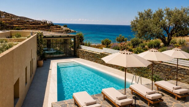 A pool area with lounge chairs and umbrellas, overlooking a coastal landscape.