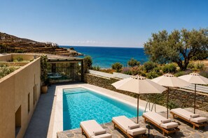 A pool area with lounge chairs and umbrellas, overlooking a coastal landscape. - Domotel Kea (Kea)