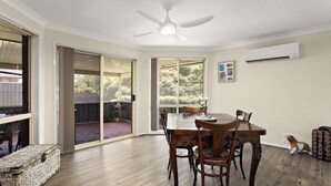 A room with a dining table, chairs, a ceiling fan, an air conditioning unit, and a sliding glass door leading to an outdoor area. - Modern 4BR Muswellbrook Stay (Muswellbrook)