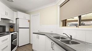 A modern kitchen with white cabinets, a stainless steel sink, and a window providing natural light. - Modern 4BR Muswellbrook Stay (Muswellbrook)