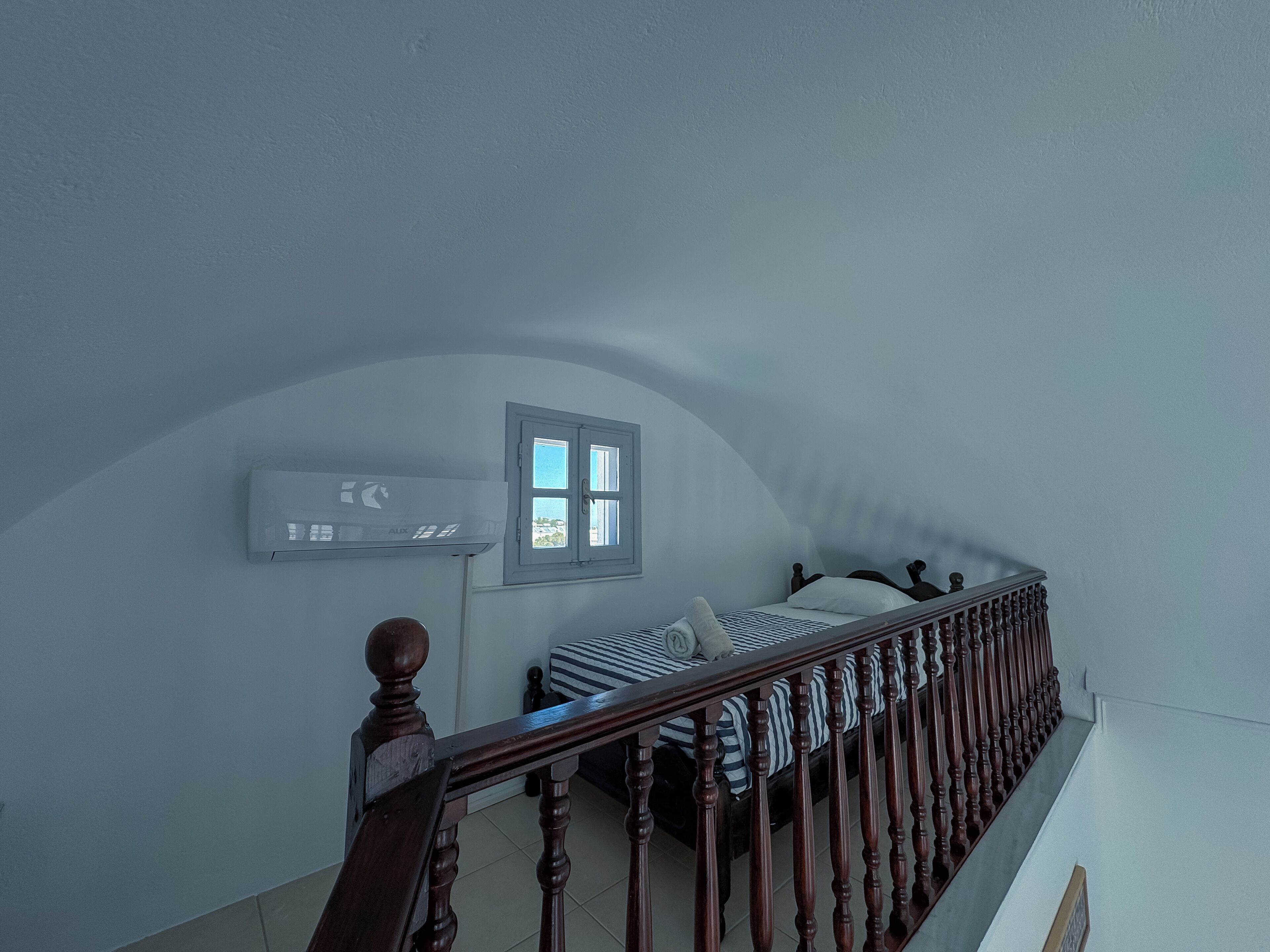 A bedroom with a bed, a window, and a wall-mounted air conditioner.