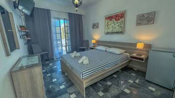 A hotel room with a bed, bedside lamps, a desk, a chair, and artwork on the walls.