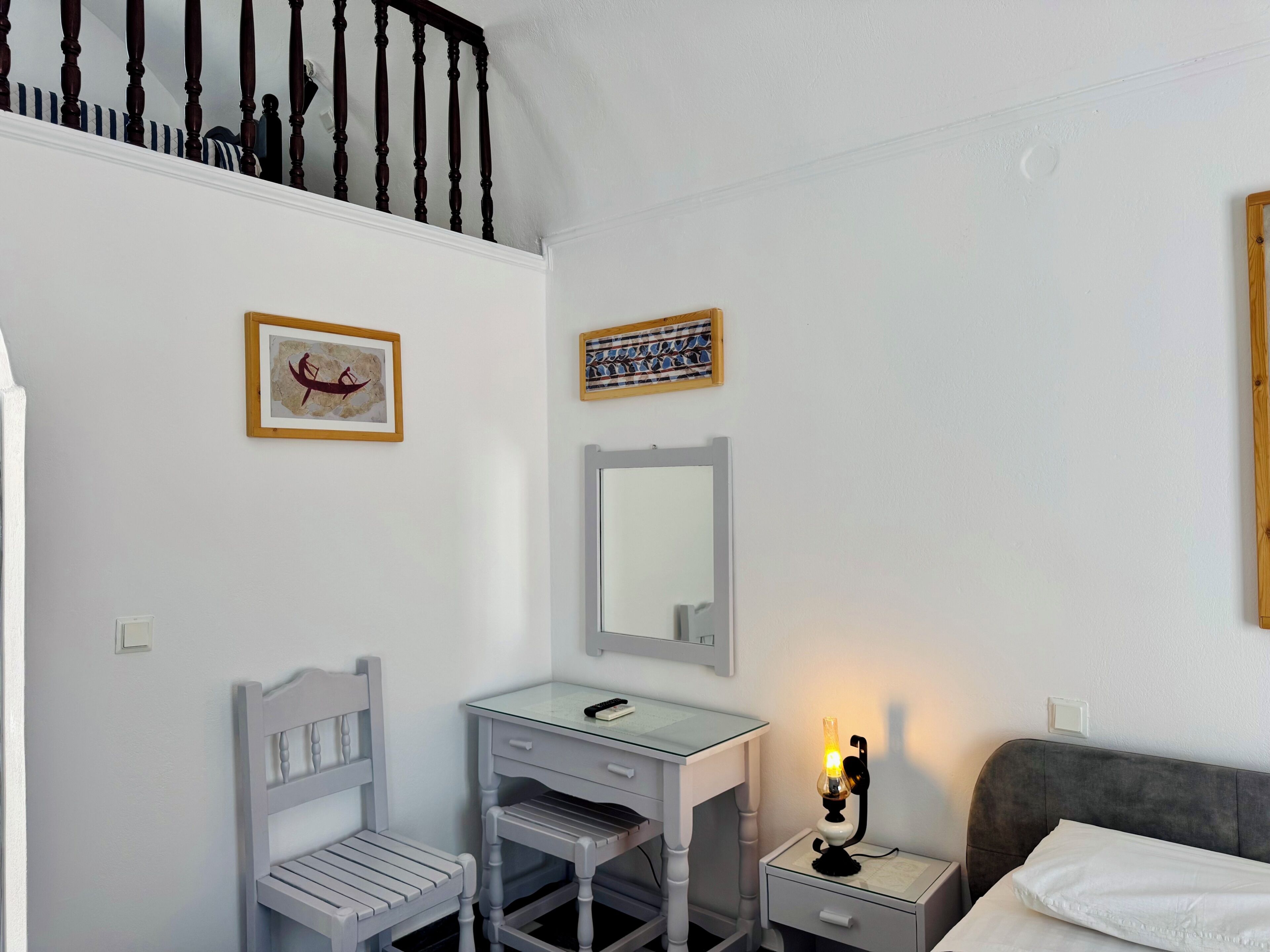 Ein Schlafzimmer mit einem Bett, einem Schreibtisch mit Stuhl, einem Nachttisch mit Lampe und einer Treppe.