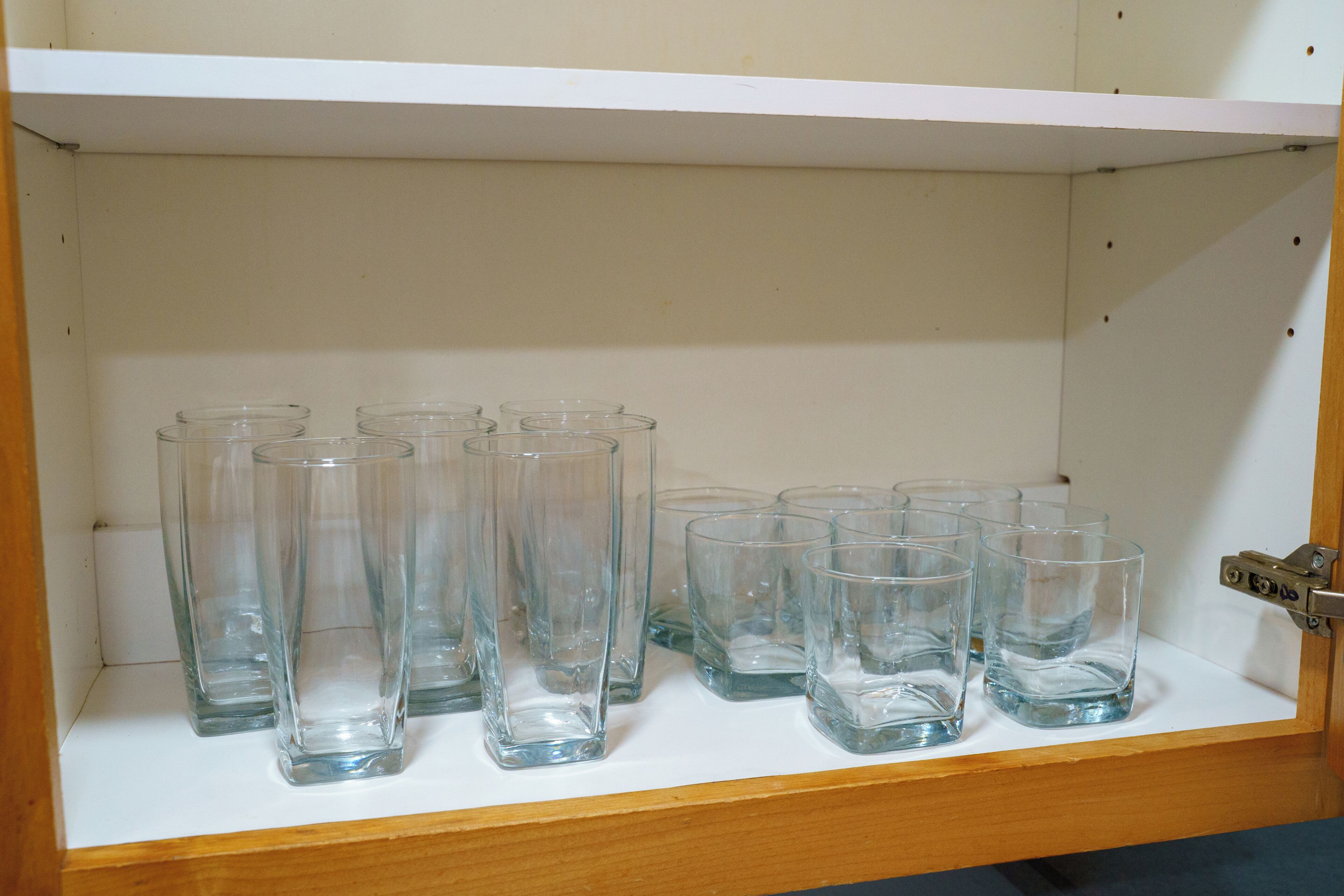 A shelf with multiple clear glass tumblers.