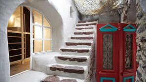 Eine Treppe mit weißen Stufen und roten Türen, die zu einem Raum mit Holzboden und einem Fenster führt.