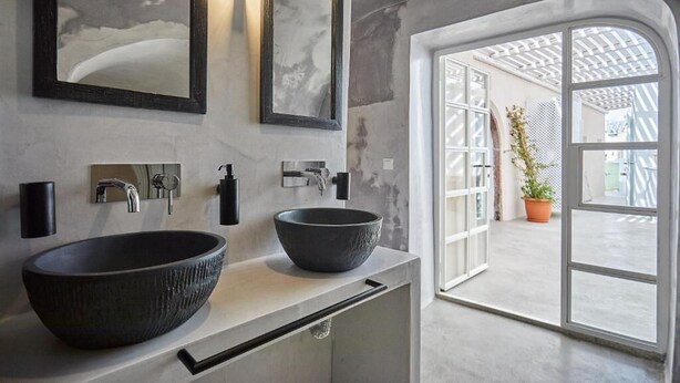 Ein modernes Badezimmer mit zwei Aufsatzwaschbecken, einem großen Spiegel und Blick auf einen Außenbereich mit einem Blumentopf.