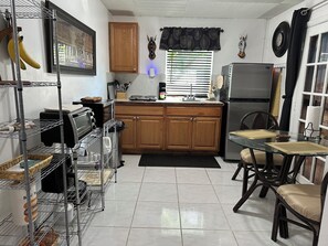 Una cocina con armarios de madera, un refrigerador de acero inoxidable, un tostador y una mesa de comedor con sillas.