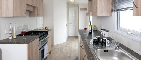 Una cocina moderna con una isla central, pileta de acero inoxidable y armarios de madera.