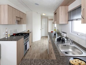 Eine moderne Küche mit einer zentralen Kochinsel, Spüle aus Edelstahl und Holzschränken.