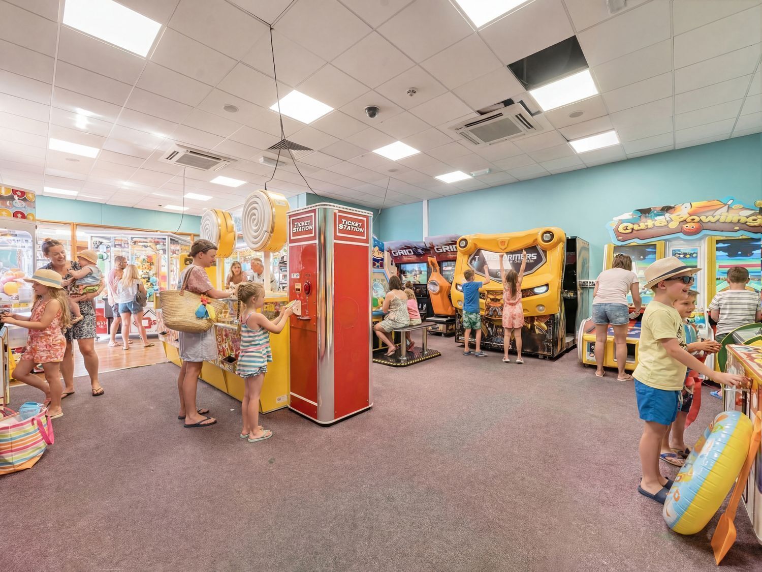 Ett inomhusnöjescenter med olika spelautomater, utlämningsställen för vinstbiljetter och ett golv täckt med matta.