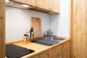 A compact kitchen with wooden cabinets, a sink, a cutting board, and a built-in stovetop. - Ragione - City Center Apt by Wonderful Italy (Catania)