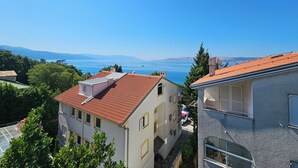 Un quartier résidentiel avec des immeubles, un ciel bleu dégagé et une vue lointaine sur une étendue d’eau.