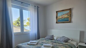 Une chambre à coucher avec un lit, une table de chevet, un tableau et une fenêtre avec des rideaux.