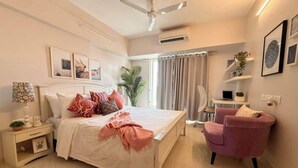 Een slaapkamer met een bed, nachtkastje, stoel en een plafondventilator.