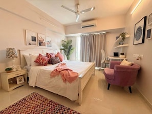 A bedroom with a bed, bedside table, chair, and a ceiling fan. - 5 Star Luxury ✪  Pool, Gym ✪ Near Airport ✪ BKC ✪ (Mumbai)