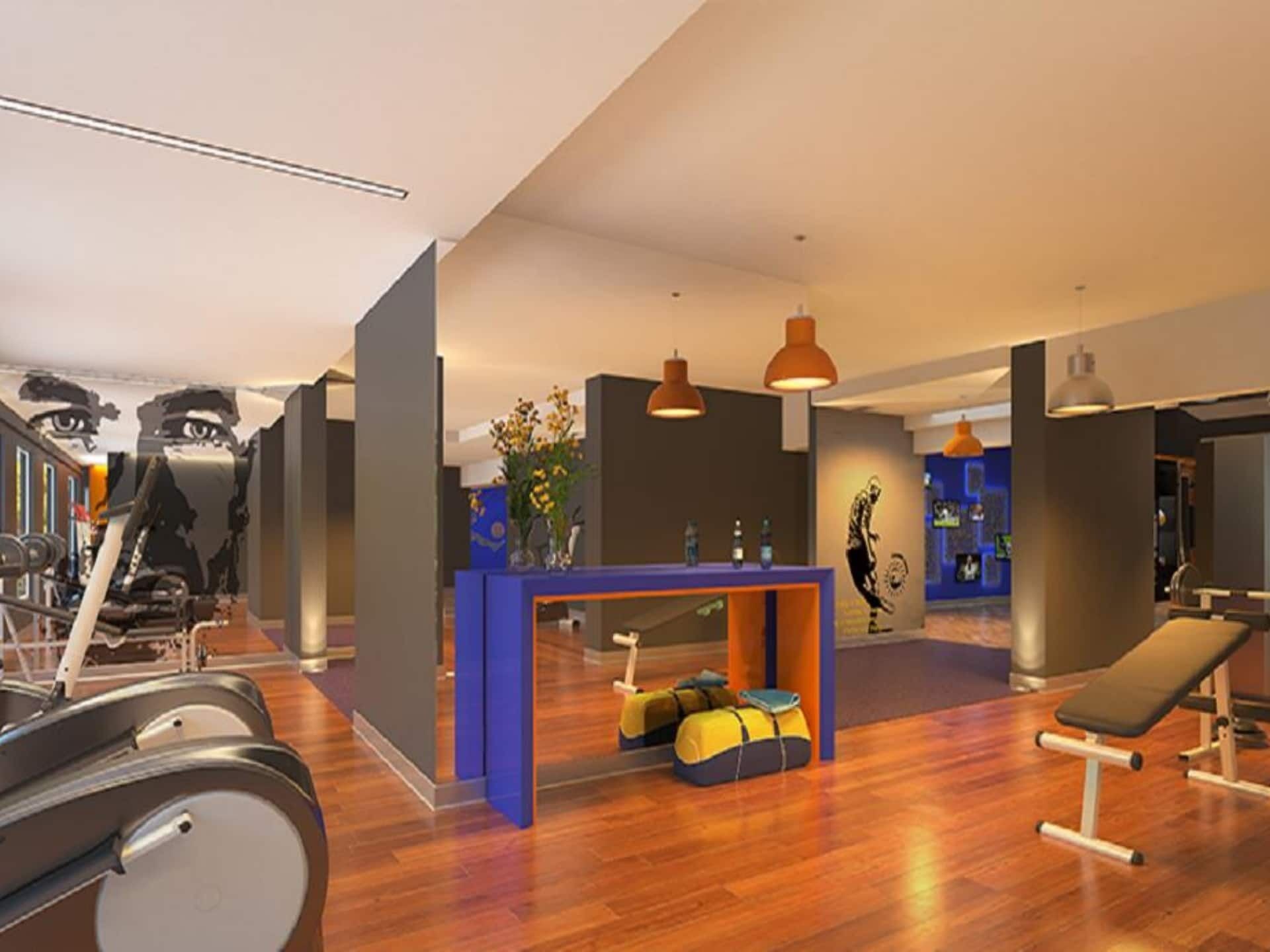 A gym with exercise equipment, a reception desk, and a bench.