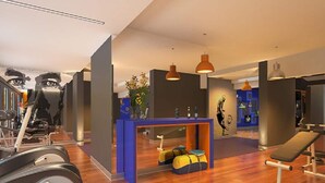 Een fitnessruimte met trainingsapparatuur, een receptiebalie en een bank.