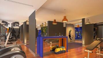 A gym with exercise equipment, a reception desk, and a bench.