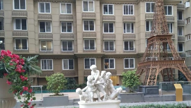 Een binnenplaats met een standbeeld, een replica van de Eiffeltoren, en een gebouw met veel ramen.
