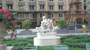 A courtyard with a statue, a replica of the Eiffel Tower, and a building with multiple windows.
