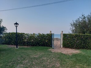 A pathway leading to a beach, flanked by a hedge and a lamp post. - 145 Emerald Beach, 1-7 (Denia)