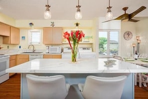 Een moderne keuken met een centraal eiland, witte kastjes en hanglampen.