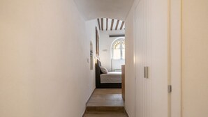 A narrow hallway with wooden steps leading to a bedroom with a bed and a window. - Charming studio apartment for two, renovated and located in a period building near Porta Ovile, one of the most convenient access points to the medieval heart of Siena. Its strategic location allows you to reach Piazza del Campo in about a 10-minute walk (Siena)