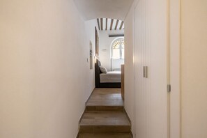 A narrow hallway with wooden steps leading to a bedroom with a bed and a window. - Charming studio apartment for two, renovated and located in a period building near Porta Ovile, one of the most convenient access points to the medieval heart of Siena. Its strategic location allows you to reach Piazza del Campo in about a 10-minute walk (Siena)