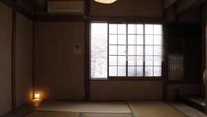 Una habitación tradicional japonesa con suelo de tatami, puertas correderas y ventana con vidrio esmerilado.