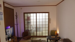 Una sala de estar con televisor, un sofá, un tapete de estampado de leopardo y un ventanal corredero.
